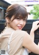 A young woman leaning against a wooden fence.