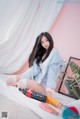 A woman sitting on a bed next to a bottle of soda.