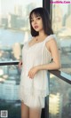 A woman in a white dress standing on a balcony.