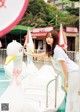 A woman standing next to a white swan in a pool.