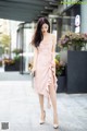 A woman in a pink dress is walking down the street.