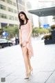 A woman in a pink dress is walking down the street.