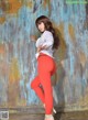 A woman in a white shirt and red pants posing for a picture.