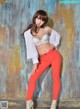 A woman in a white shirt and red pants posing for a picture.