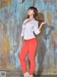 A woman in a white shirt and red pants posing for a picture.