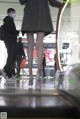 A woman wearing a face mask walking down an escalator.