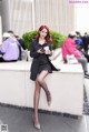 A woman sitting on a wall holding a cup of coffee.