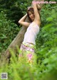 A woman leaning against a tree in the woods.