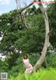 A woman standing next to a tree in a field.