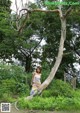 A woman standing next to a tree in a forest.