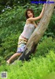 A woman leaning against a tree in the woods.