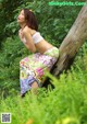 A woman leaning against a tree in a field of flowers.