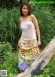 A woman in a white top and colorful skirt posing for a picture.