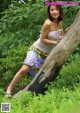 A woman leaning against a tree in the woods.